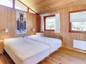 A wooden-paneled room with a double bed, a window with curtains, and a wall-mounted light fixture. - 6 Person Holiday Home in Blokhus (Blokhus)