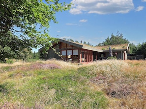 Uma casa moderna com uma grande janela de vidro, emoldurada por paisagem natural.