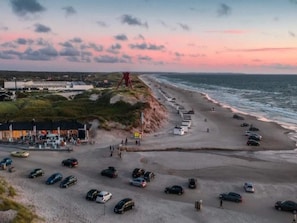 A beach with a parking lot and a building with a sign. - 6 Person Holiday Home in Blokhus (Blokhus)