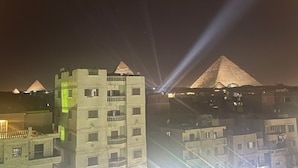 Yökuva kaupunkimaisemasta, jossa taustalla näkyy useita pyramideja ja etualalla parvekkeilla varustettu rakennus.