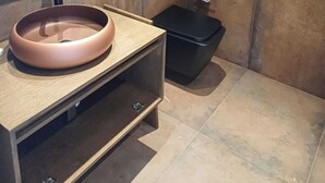 A modern bathroom with a round sink, a mirror, and a black trash bin. - Princi Potes Luxury Suites (Ksamil)