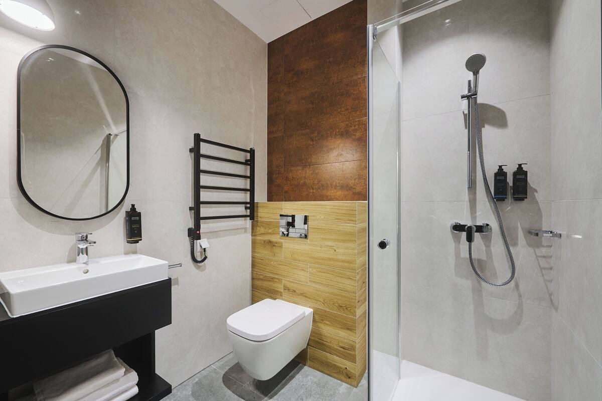 Une salle de bain moderne avec un lavabo blanc, des toilettes et un espace douche.