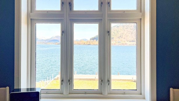 A large window with multiple panes offering a view of a lake and distant mountains. - 7 Person Holiday Home in Gurskoy (Heroy)