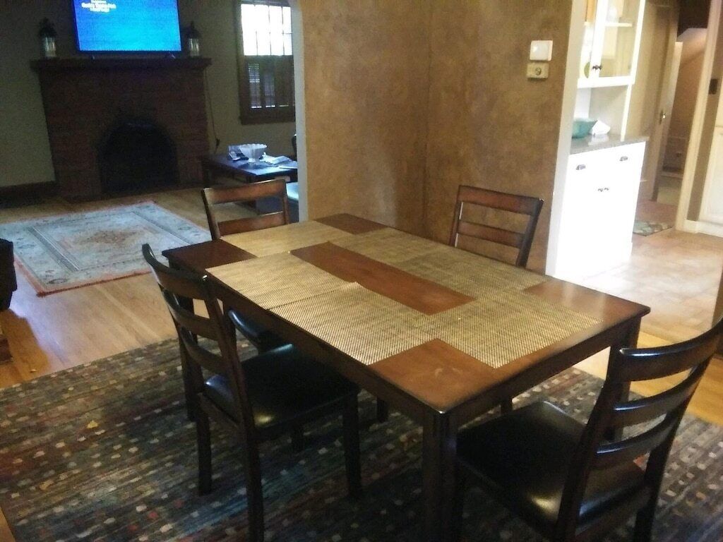 A dining area with a rectangular table, four chairs, a fireplace, and a television in the background.