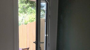 A bedroom with a bed, a chair, and a table outside a sliding glass door. - Joli Appartement à 50 Mètres de la Plage et Proche D'un Port de Pêche Typique (Saint-Pierre-d'Oléron)