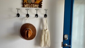 Un banc en bois, une porte bleue, une pancarte d’accueil et un chapeau suspendu à des crochets.