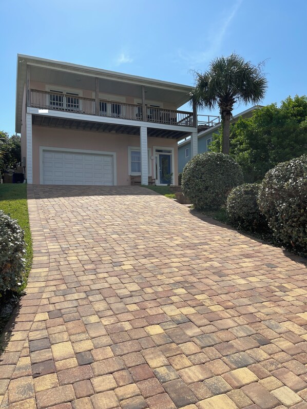 A two-story house with a paved driveway leading to a garage.
