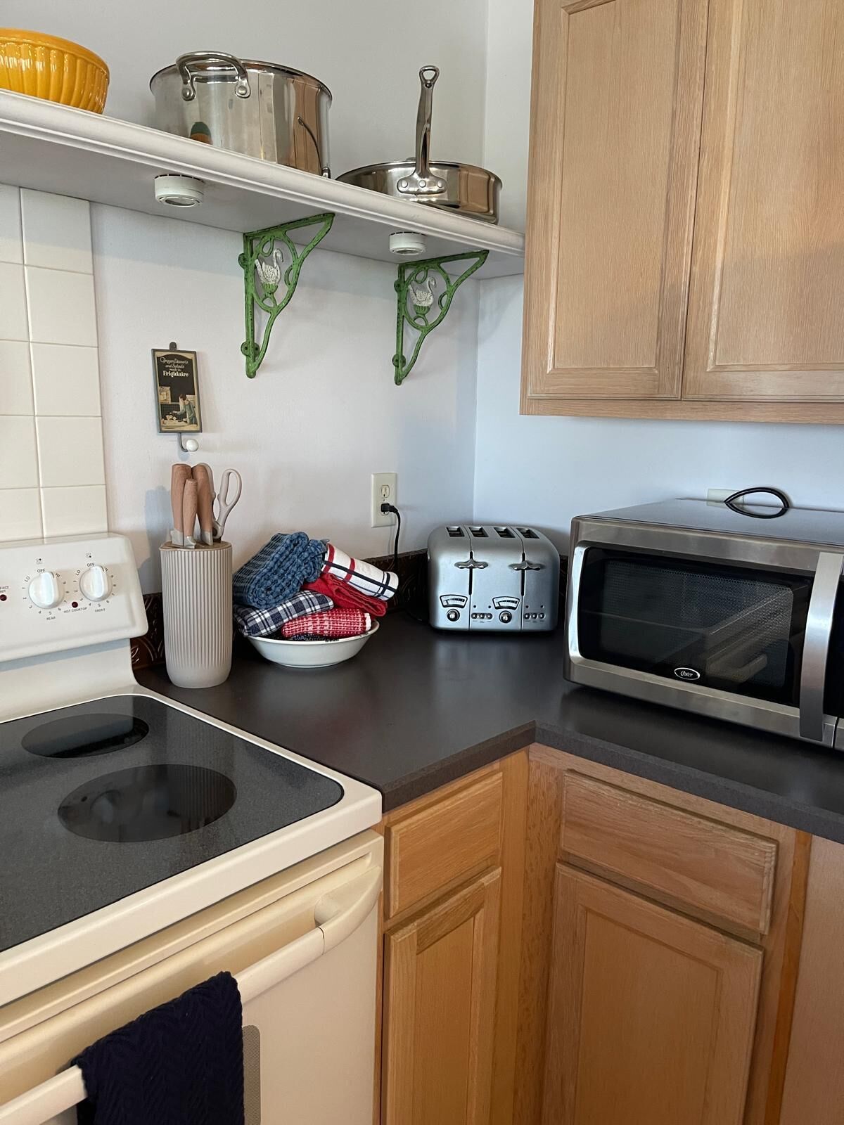 A kitchen with a stove, toaster, oven, and various kitchen items on the counter.