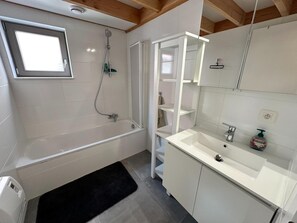 Une salle de bain moderne équipée d’une baignoire, d’une douche, d’un lavabo et d’un miroir.