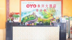 A hotel reception desk with a large sign, a plant, and a small statue. - Oyo Yongxing Hotel (Loudi)