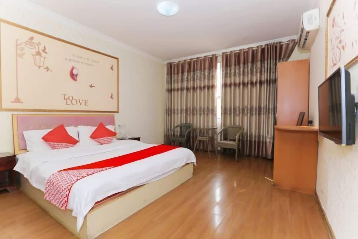 Una habitación de hotel con cama, televisión, escritorio y silla.