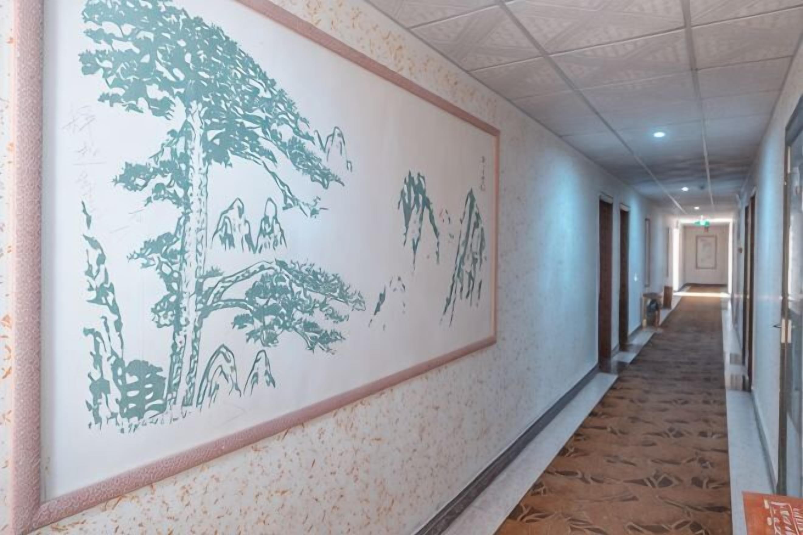 Un pasillo con un gran mural en la pared, suelo alfombrado y puertas a la derecha.