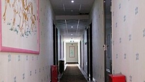 A long, narrow hallway with patterned wallpaper, a red fire extinguisher, and a door at the end. - Oyo Yongxing Hotel (Loudi)
