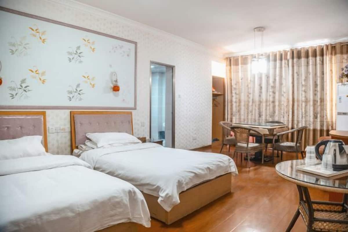 Una habitación de hotel con dos camas, una zona de comedor con mesa y sillas, y una cocina.