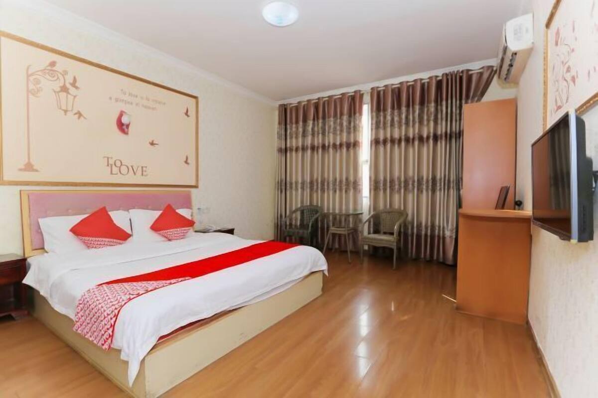 Una habitación de hotel con cama, televisión, escritorio y silla.