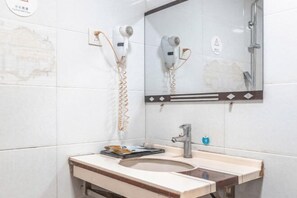 A bathroom with a sink, mirror, and two hair dryers mounted on the wall.