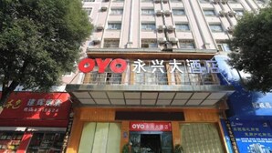 A hotel with a prominent 'OYO' sign, featuring a modern facade with large windows and a balcony. - Oyo Yongxing Hotel (Loudi)