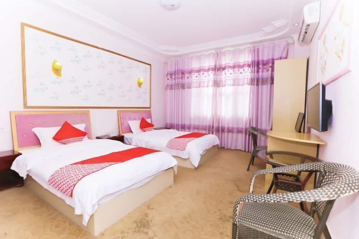 Habitación de hotel con dos camas, un escritorio, una silla y un televisor.