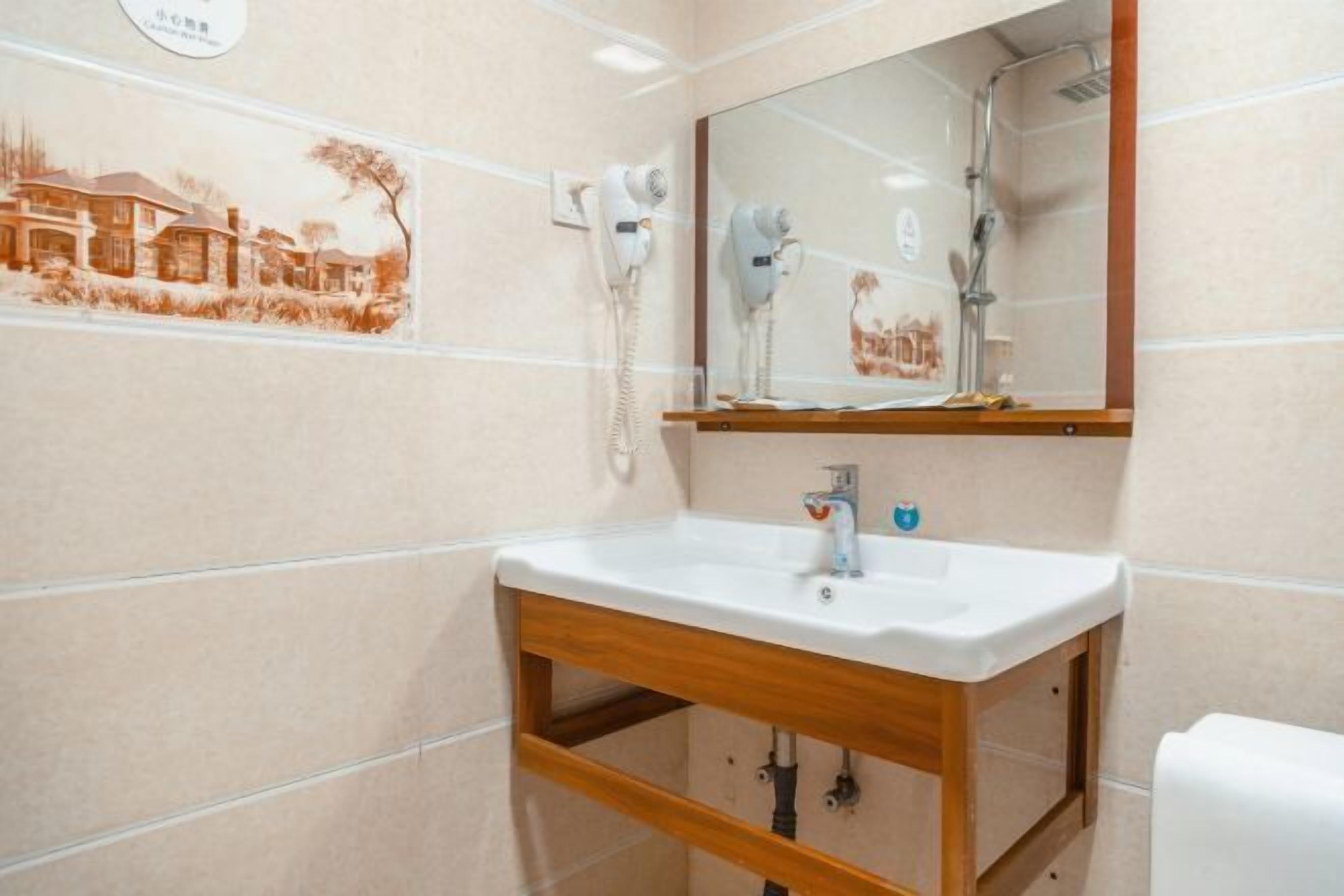 A bathroom with a white sink, a mirror, and a hairdryer mounted on the wall.