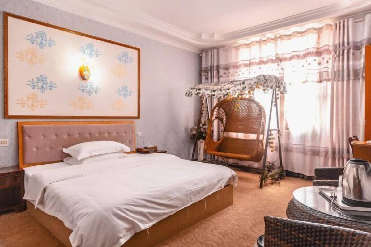 Una habitación de hotel con cama, una silla, una mesa y un papel tapiz con motivos florales.