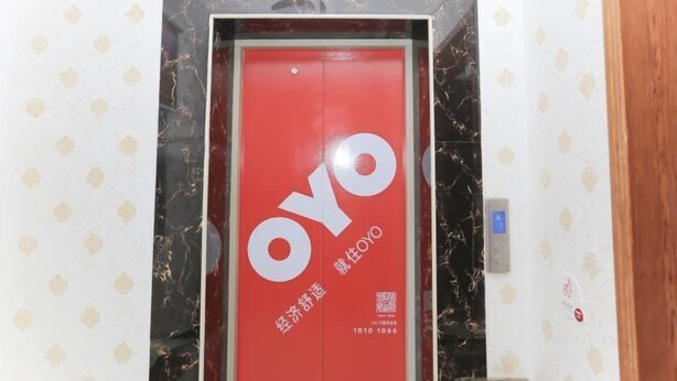 A red elevator door with the OYO logo and QR code. - Oyo Yongxing Hotel (Loudi)