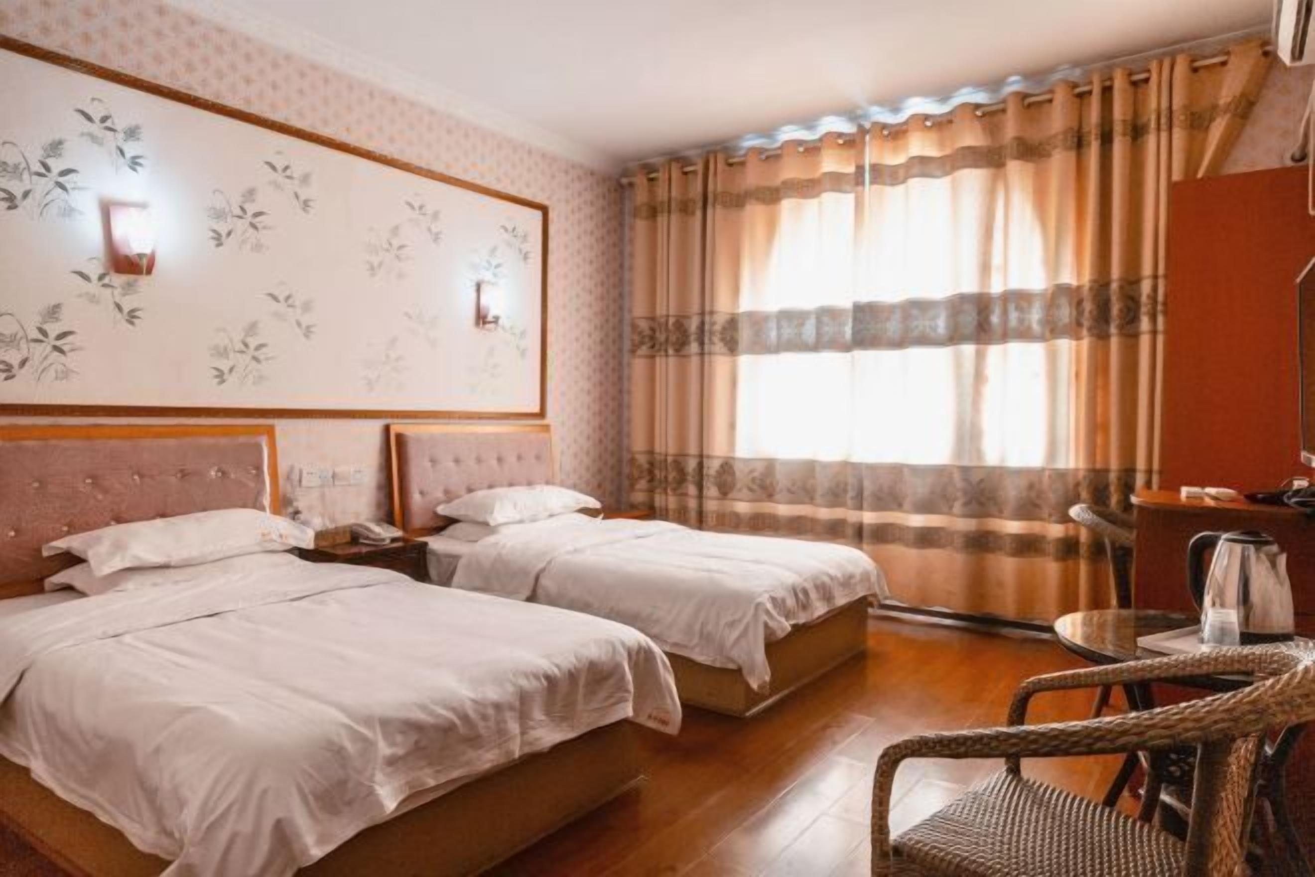 A hotel room with two beds, a large wall-mounted artwork, a desk with a chair, and a window with curtains.