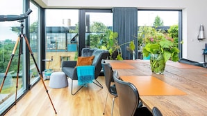 Un salon moderne avec une grande table en bois, des sièges confortables et un trépied posé sur le sol.