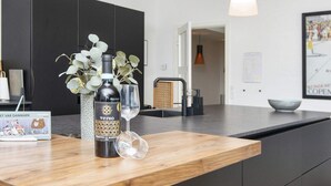Une cuisine moderne avec un plan de travail en bois, une bouteille de vin et un verre.