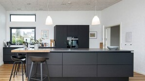 Une cuisine moderne dotée d’un grand îlot central, de tabourets de bar et de luminaires suspendus.