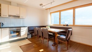 Une cuisine moderne dotée d’un four encastré et d’un coin repas avec une table et des chaises en bois.