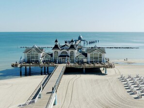 Un muelle con un edificio grande, con múltiples ventanas y una cúpula, que se extiende hacia el mar.