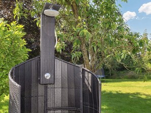 Ein schwarzer Grill für den Außenbereich mit Schornstein, umgeben von viel Grün.