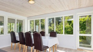 A dining area with a table and chairs, large windows, and a view of greenery outside. - 4 Star Holiday Home in Gedsted (Gedsted)