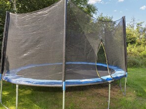Un trampoline doté d’un filet de protection et installé à l’extérieur.
