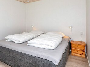 A double bed with white bedding, a grey blanket, and a wooden nightstand with drawers. - 4 Star Holiday Home in Gedsted (Gedsted)