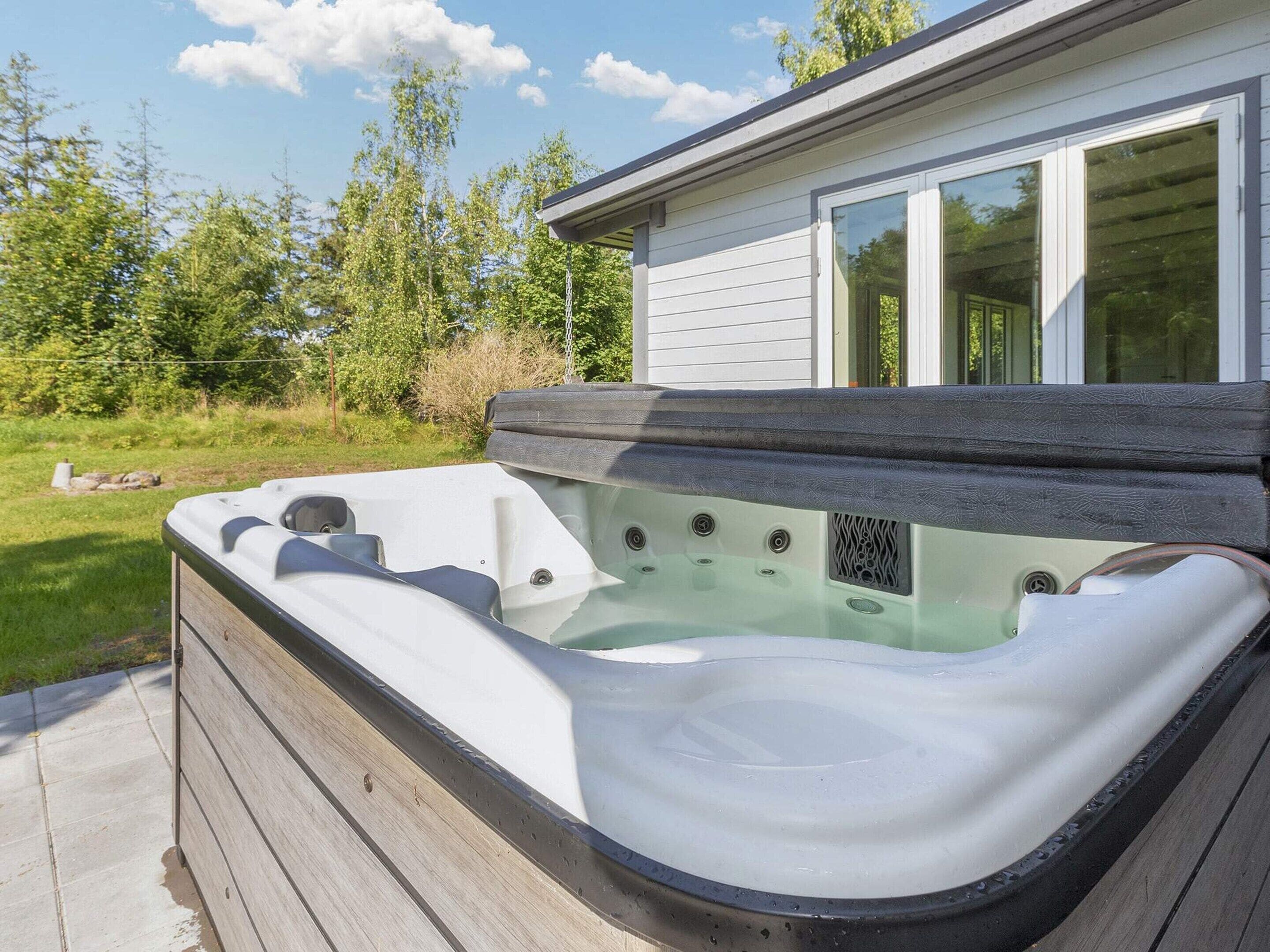 Ein Whirlpool neben einem Haus mit einer Holzterrasse.