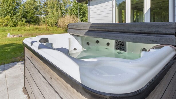 A hot tub adjacent to a house with a wooden deck. - 4 Star Holiday Home in Gedsted (Gedsted)