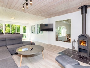 Een moderne woonkamer met een open haard, een bank, een ronde salontafel en een aan de muur bevestigde televisie.