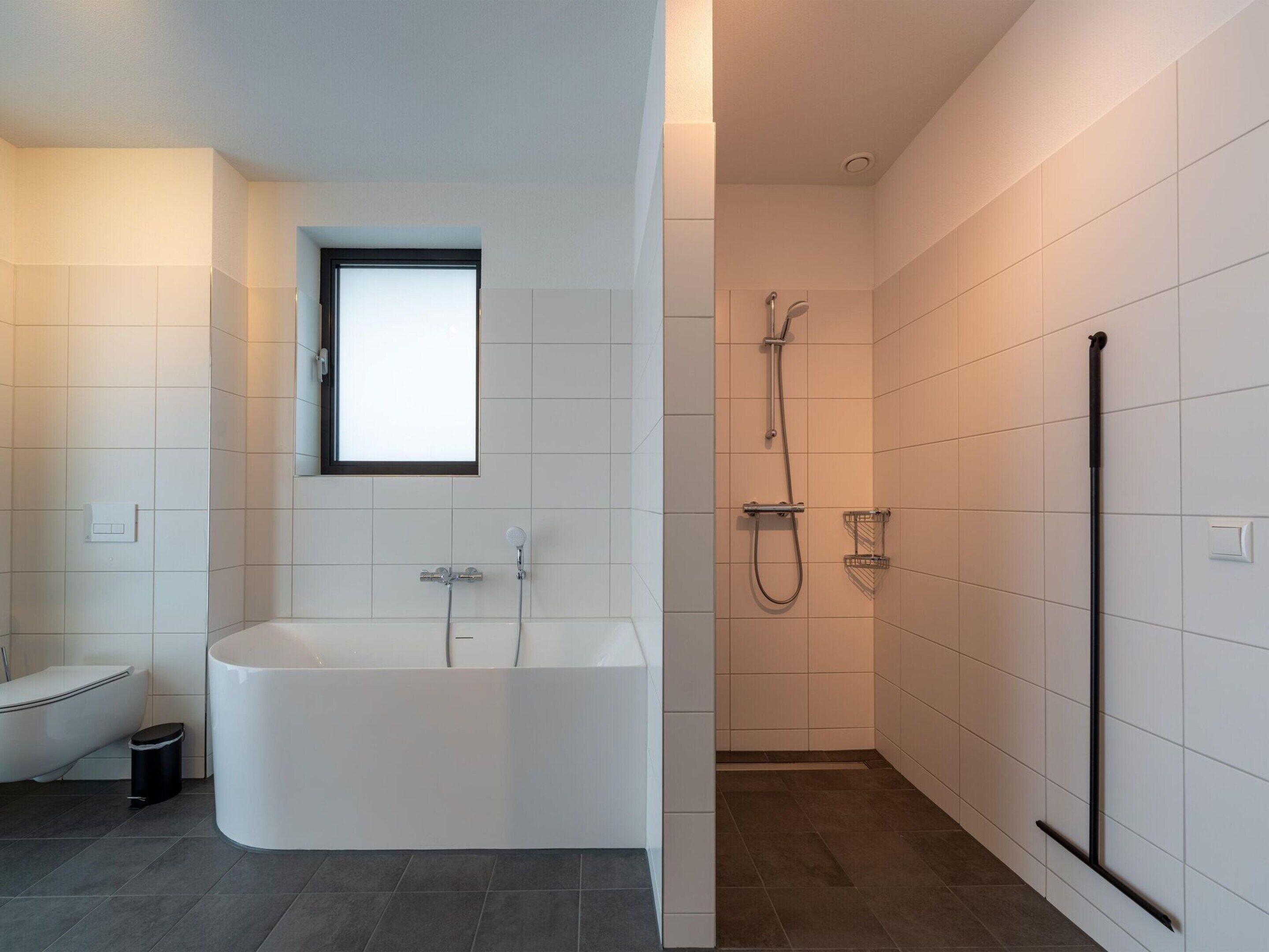 A modern bathroom with a freestanding bathtub, a toilet, and a shower area.
