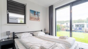 A hotel room with two beds, a large window, a painting, and a view of the outside. - Villa With Covered Terrace and Jetty on the Water (Zeewolde)