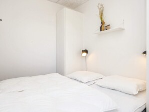Ein schlichter Schlafzimmer mit einem Bett, zwei Nachttischlampen und einem Regal mit einer Vase.