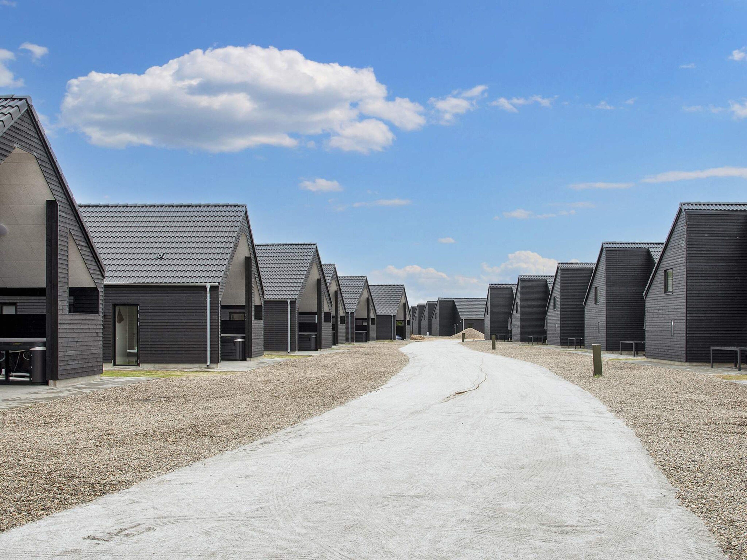 A row of modern, dark-colored buildings with a gravel path leading through them.