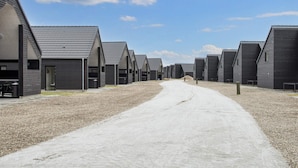 A row of modern, dark-colored buildings with a gravel path leading through them.