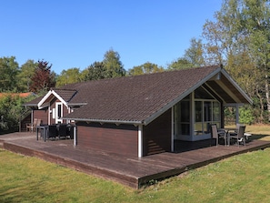 A wooden cabin with a sloped roof, a deck, and a covered outdoor seating area. - 4 Star Holiday Home in Hadsund (Hadsund)