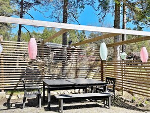 An outdoor wooden pergola with a table and chairs, surrounded by trees. - 6 Person Holiday Home in Djurhamn (Fågelbrolandet)