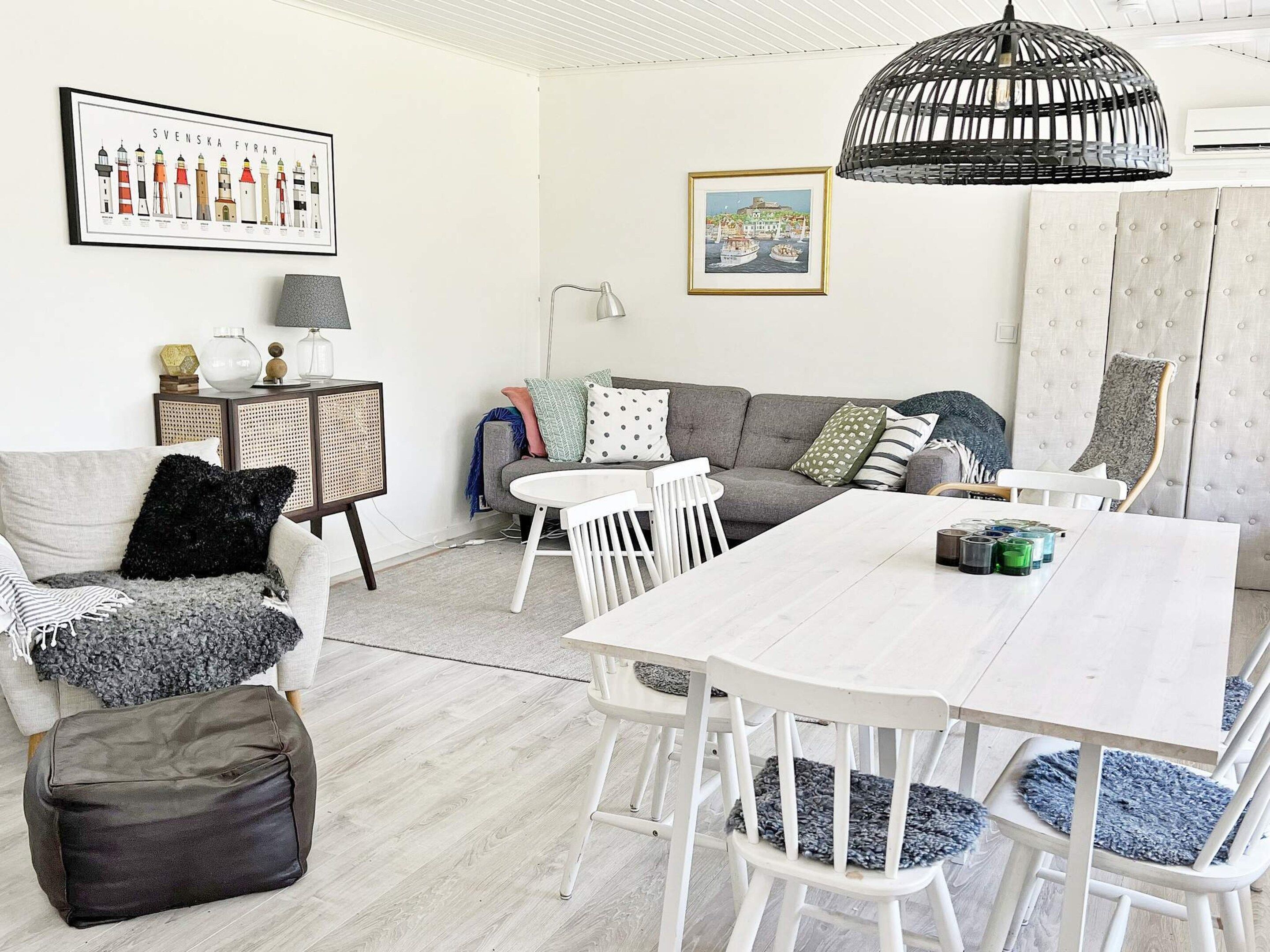 A living room with a white sofa, a dining table, and a lamp.