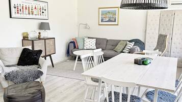 A living room with a white sofa, a dining table, and a lamp.