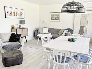 Een woonkamer met een witte bank, een eettafel en een lamp.