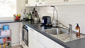 A kitchen with white cabinets, a black countertop, a stainless steel sink, a coffee maker, and a bottle of hand soap. - 6 Person Holiday Home in Djurhamn (Fågelbrolandet)
