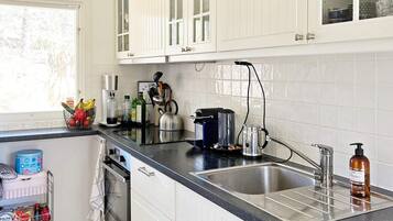 A kitchen with white cabinets, a black countertop, a stainless steel sink, a coffee maker, and a bottle of hand soap.